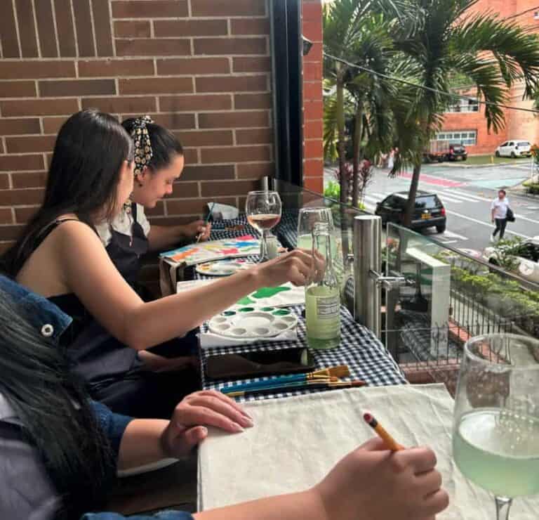 Creativos en una actividad de pintura en un restaurante con vista a la calle.