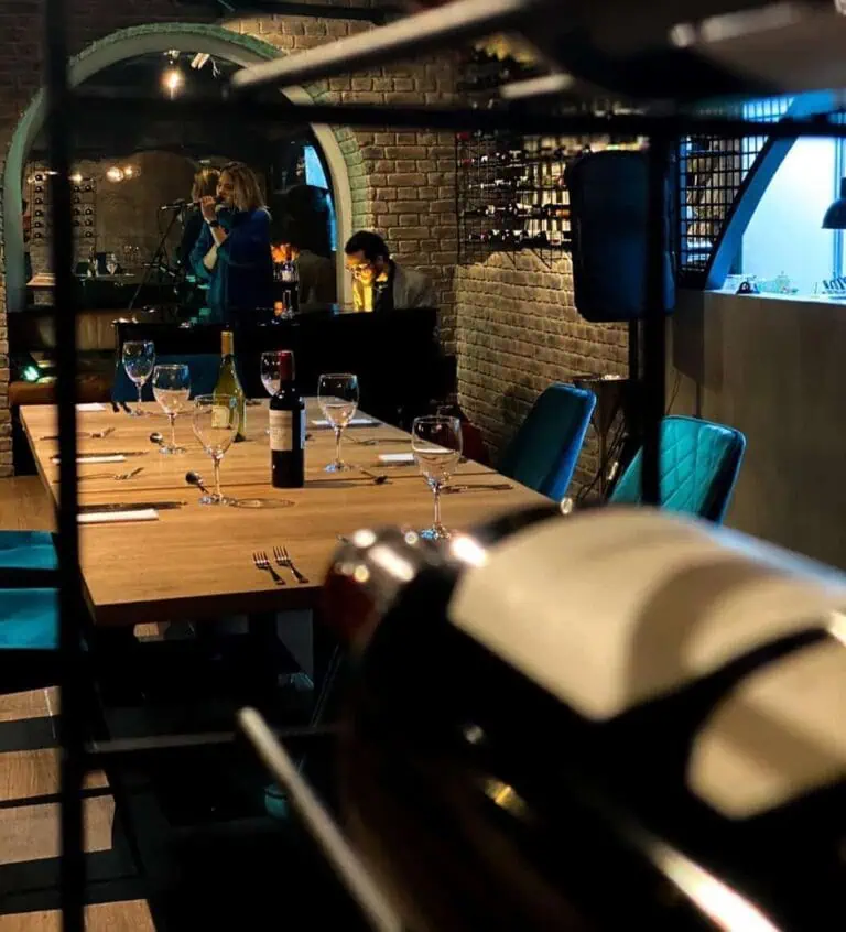 Drinks and utensils on an elegant restaurant table at an exclusive social event in a setting with brick walls and modern decor.