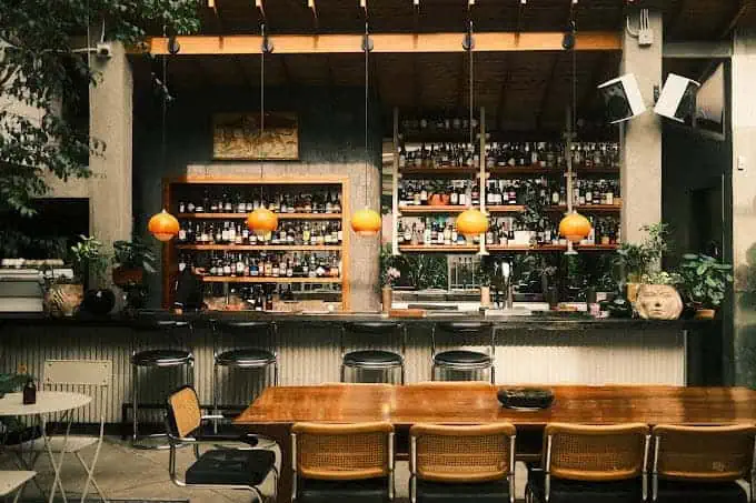 Un bar avec des étagères remplies de bouteilles et une ambiance moderne pour événements et réunions.