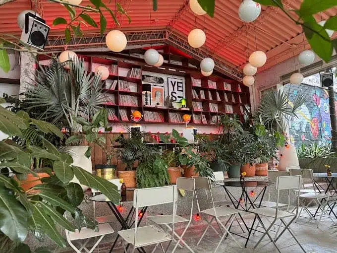 Décoration intérieure avec plantes vertes et tables événementielles dans un espace moderne avec éclairage décoratif et écran géant pour événements corporatifs et sociaux en Colombie.