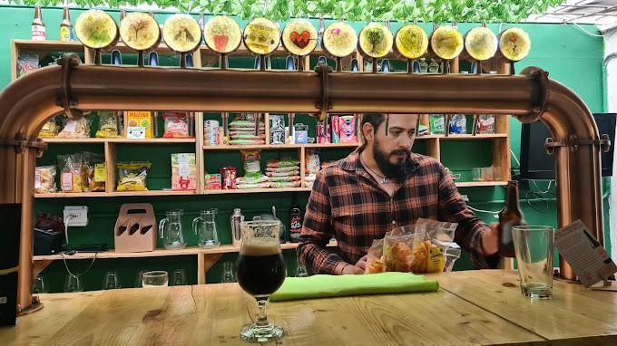 Innovador puesto de bar con selección de snacks y bebidas artesanales en un evento al aire libre en Colombia.