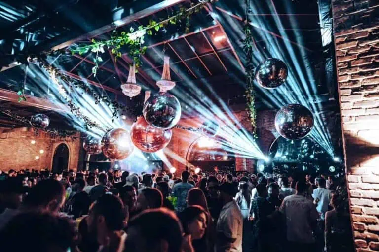Light show and DJ at a corporate event with a festive atmosphere in an industrial interior decorated with reflective balls and plants. Ideal for corporate events and parties.