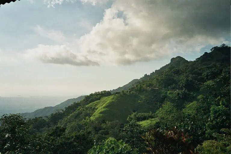 The fragrance of the green mountains in a natural Colombian landscape, with clouds and a bright sky, ideal for outdoor events and eco-tourism in the region.