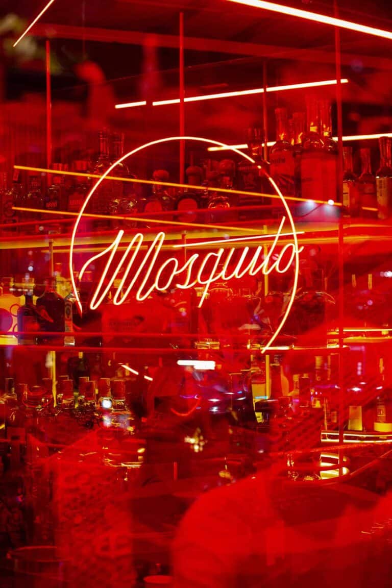 Brillo de neón rojo con el texto "Mosquito" en un bar o restaurante moderno, creando un ambiente vibrante y atractivo para eventos y fiestas nocturnas.
