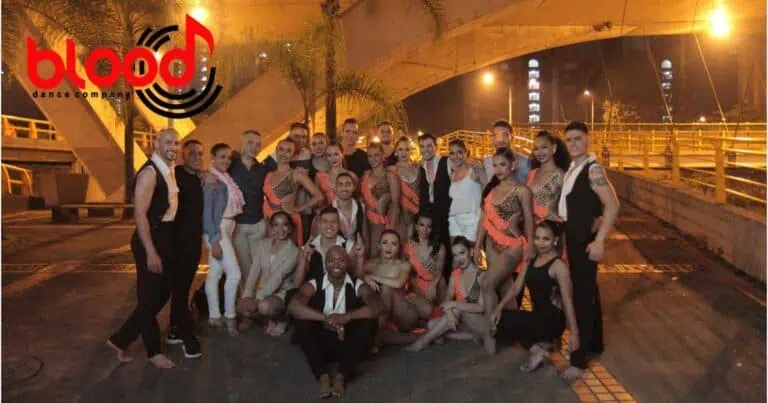 Blood Dance Company, un groupe de danseurs lors d'un événement à Bogotá, mettant en vedette des lumières nocturnes, des lumières de la ville et une scène pour la danse artistique et professionnelle dans un cadre urbain moderne.