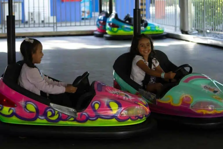 女孩们在儿童游乐场玩碰碰车。特写镜头展现了游乐园里快乐的女孩们在儿童游乐设施旁玩耍的场景。