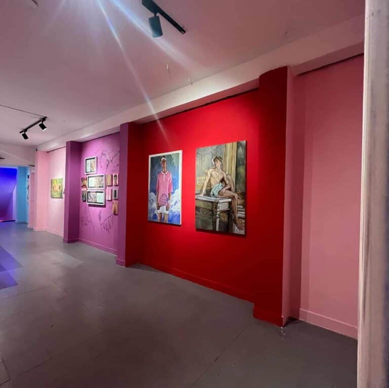 Proto de arte moderna exhibiendo obras en una galería de eventos, con paredes en tonos rosa y rojo, iluminación dirigida, creando un ambiente sofisticado para eventos culturales y artísticos en Bogotá.