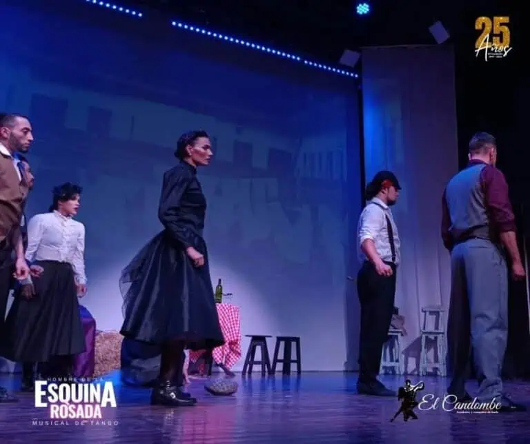 Pink Corner - Tango Musical sur scène avec des acteurs en costumes de théâtre, mettant en vedette une mise en scène dans un théâtre bleu avec des lumières vives.