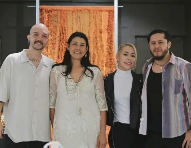 Gente en evento de networking en Colombia, con fondo de cortina anaranjada, celebrando y posando para fotografía en un ambiente profesional y amigable.