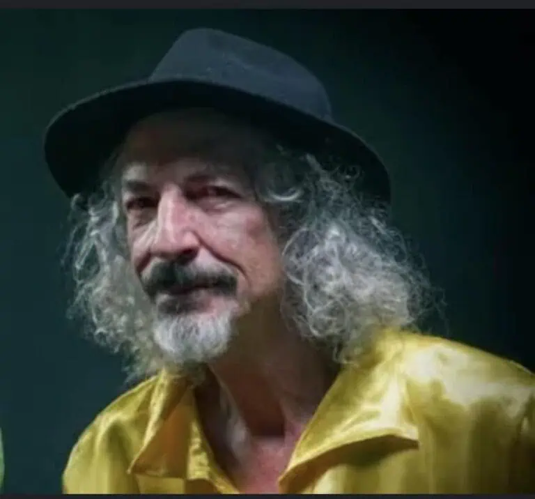 A guru with a gray beard and a black hat, an image of an older man with a bohemian look in an artistic style, a social and cultural event in Colombia, a portrait photograph.