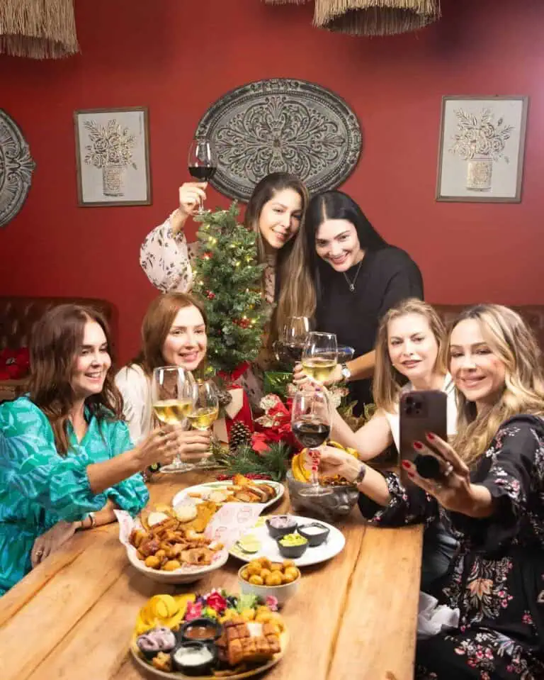 Weihnachtsfeier mit Freunden, Anstoßen mit Wein, festliche Dekorationen und traditionelles Essen, um das Jahresende in warmer Atmosphäre zu feiern.