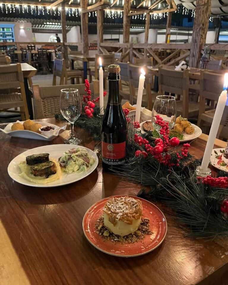 Bebida de vino espumoso rodeada de platos de comida navideña y decoraciones festivas en un ambiente cálido y acogedor para eventos especiales.