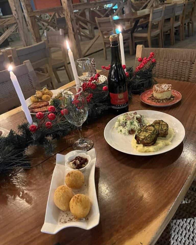 Fiesta navideña con comida gourmet, velas y decoración festiva en un ambiente cálido y acogedor para eventos especiales.
