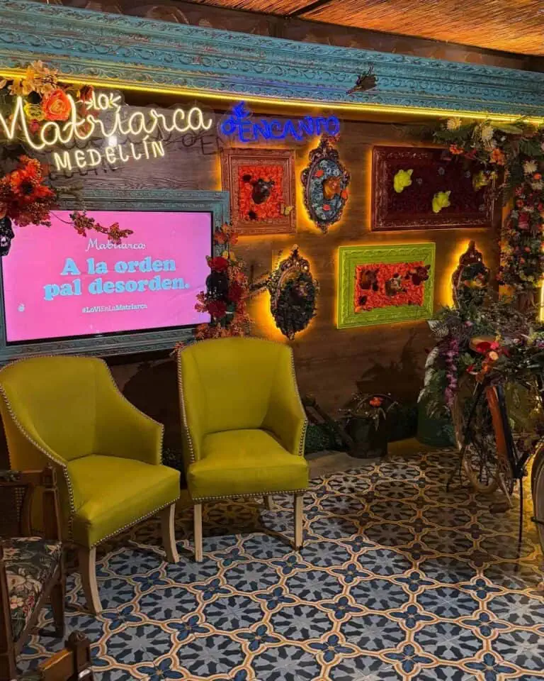Dekoratives Arrangement mit limettengrünen Sesseln, mit Rahmen und Blumenschmuck geschmückten Wänden, Paravents und Neonschildern für Veranstaltungen in Medellín.