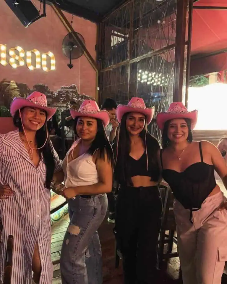 Des filles portant des chapeaux roses et des vêtements décontractés lors d'une fête dans un restaurant à thème avec un décor coloré et une ambiance festive.
