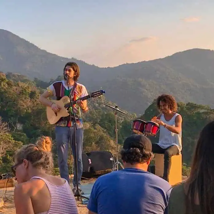 Live-Sound mit Musikern, die auf einer Freilichtbühne in einer natürlichen Umgebung mit Bergen Gitarre und Schlagzeug spielen.