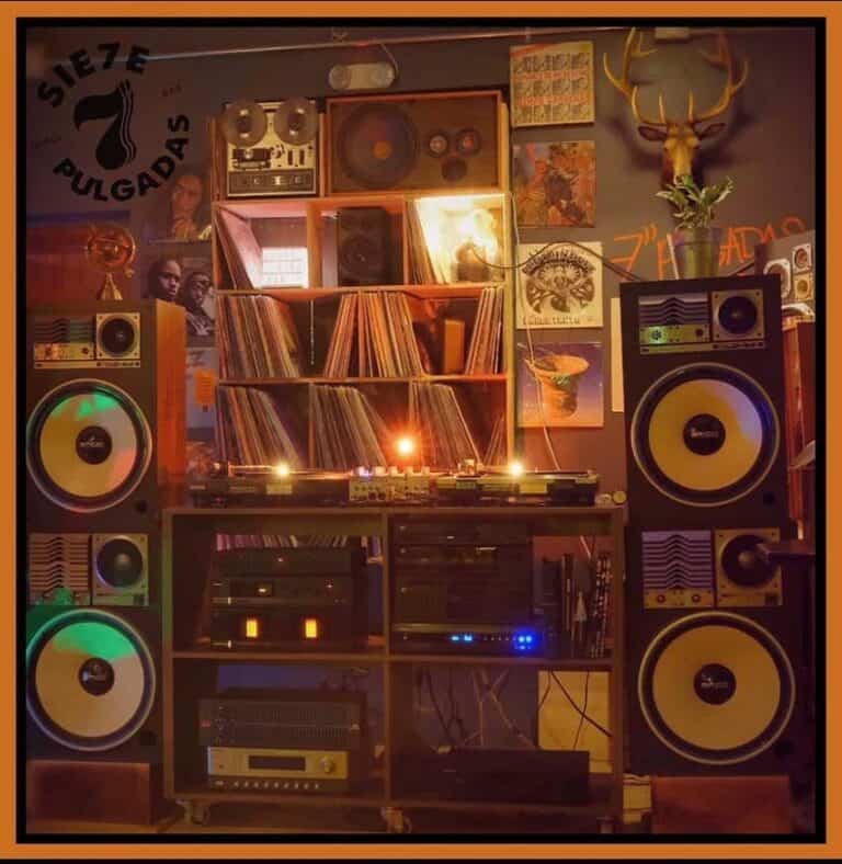 Sonido profesional con altavoces y equipo de DJ en un espacio decorado con vinilos, posters y decoraciones vintage para eventos musicales y fiestas en Bogotá.