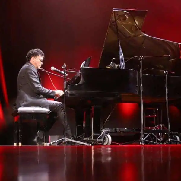 键盘手在红色灯光的舞台上演奏钢琴。