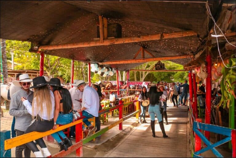 Banda de personas en feria o evento al aire libre con decoración festiva y música en vivo en un ambiente familiar y colorido en Colombia.
