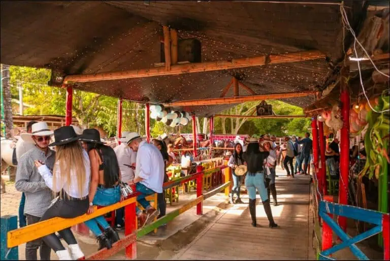 在哥伦比亚，一群人参加集市或户外活动，现场装饰喜庆，有现场音乐表演，营造出适合家庭的缤纷氛围。