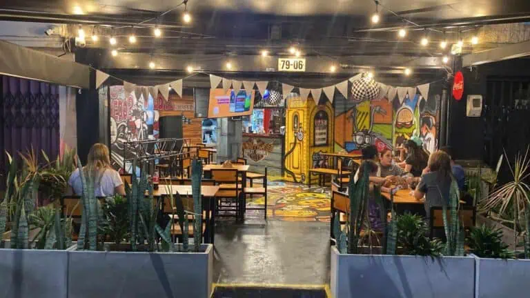 餐厅内有一幅色彩缤纷的涂鸦壁画，一群人正在享受美食，餐厅装潢现代，氛围轻松随意。