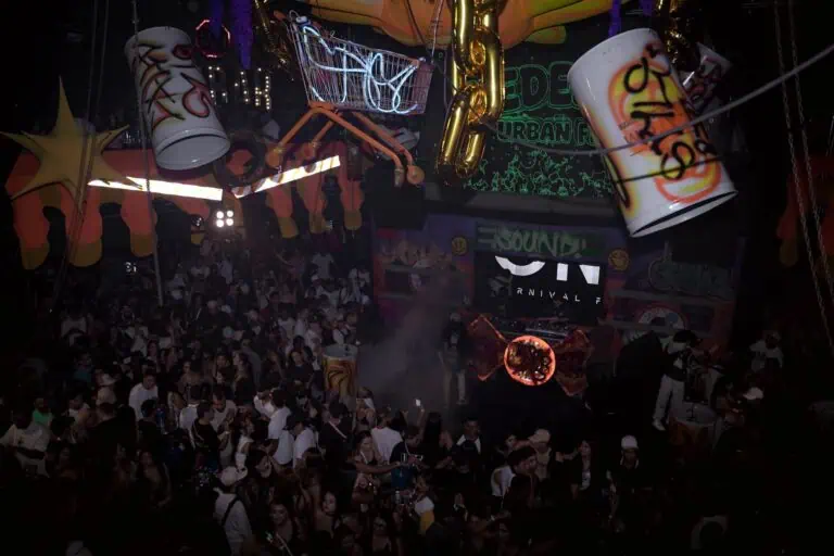 Ambiance événementielle colorée avec décor urbain, néons et une foule nombreuse profitant de musique live dans un espace de fête et de divertissement.