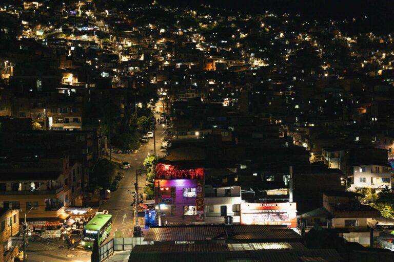Vistas nocturnas de una ciudad en colina con calles iluminadas y edificios residenciales, mostrando un ambiente urbano vibrante y animado en la noche en Bogotá, Colombia.
