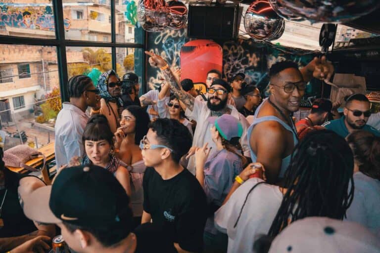 Personas en evento social con música y ambiente festivo en espacio interior con vista urbana, ideal para registros de eventos, conciertos, y experiencias culturales, promoviendo el servicio de organizacion de eventos.