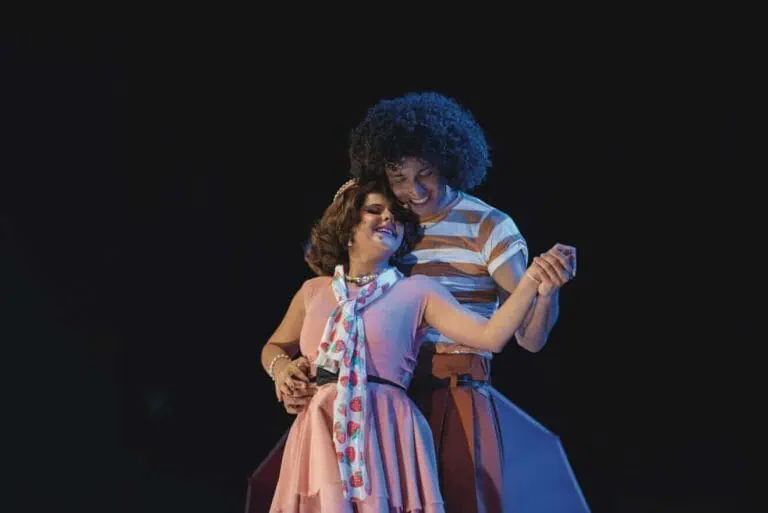 Mädchen und Frau tanzen auf einer Theaterbühne und genießen eine Live-Aufführung in einer dunklen Umgebung, in der das Licht auf sie gerichtet ist.