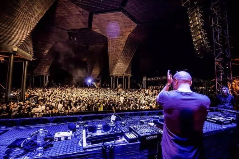 Spectacle de musique live avec un DJ lors d'un festival en plein air, entouré d'une foule nombreuse dans un lieu innovant et architecturalement époustouflant en Colombie.