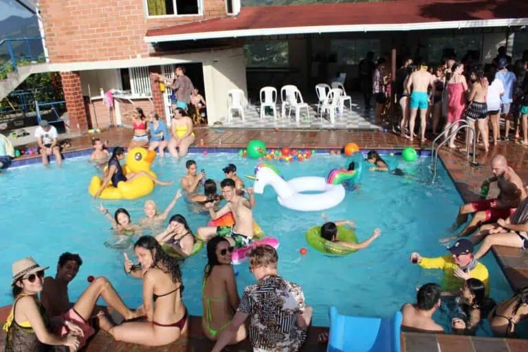 Événement ludique autour d'une piscine avec structures gonflables et beaucoup de monde profitant de l'été dans un espace social et récréatif.