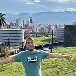 Enjoying a sunny day at Parque y Ciudad, with a panoramic view of Bogotá, surrounded by nature, with mountains and urban buildings as a backdrop, in a public recreational space.