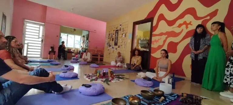 Meditação em grupo em uma sala interna colorida com símbolos espirituais e pessoas em posição de lótus, workshop de yoga e bem-estar, atenção plena e desenvolvimento pessoal em uma atmosfera relaxante e harmoniosa.