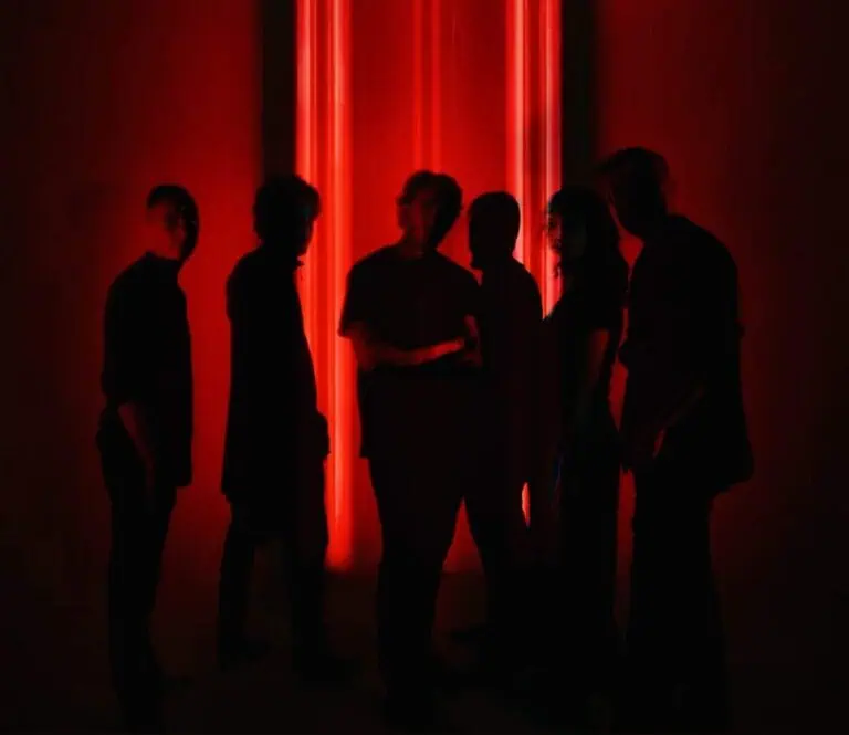 Des jeunes lors d'un événement de réseautage avec un éclairage rouge, un groupe de personnes discutant dans un cadre moderne et artistique à Bogotá.