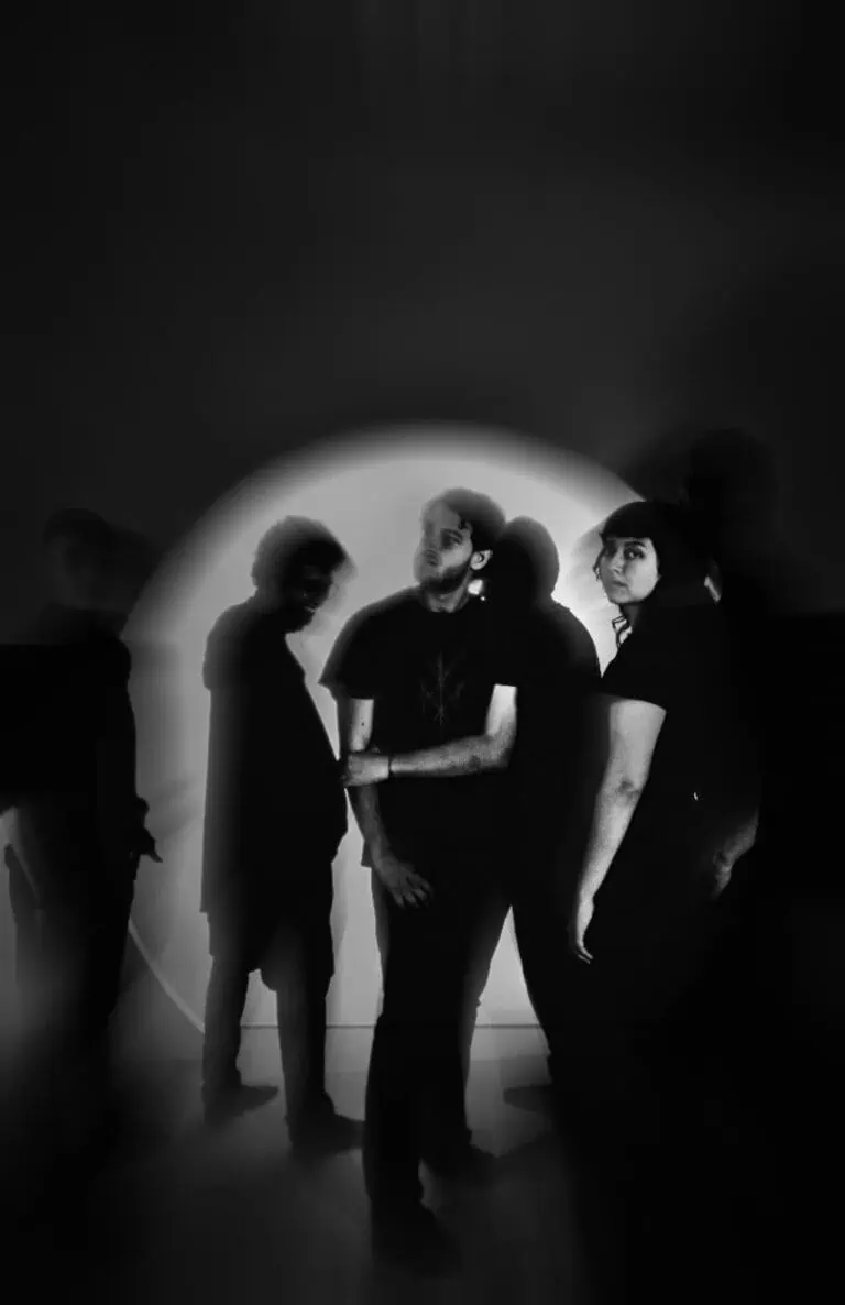 Image d'un groupe de cinq personnes dans un environnement sombre, avec un éclairage focal mettant en valeur leurs silhouettes noires et blanches, créant un effet artistique et moderne pour les événements, les artistes ou les projets créatifs.