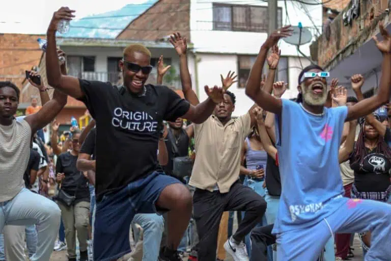 Joie lors d'un événement communautaire dans un quartier ouvrier, des gens qui dansent et s'amusent, promotion de la culture et de l'emploi à Bogotá, et un événement social et artistique dans un espace urbain ouvert.