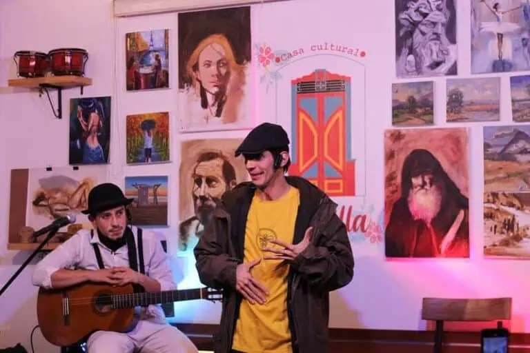 Menschen genießen Musik in einer Kunstgalerie im Casa Cultural. An den Wänden hängen Gemälde und Kunstwerke, die eine kulturelle und künstlerische Atmosphäre in Kolumbien schaffen.