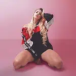 年轻女孩在粉色背景的摄影棚里摆姿势，身穿现代运动服，展现都市风格和自信态度，非常适合在哥伦比亚推广活动和都市时尚。