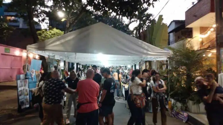 Des personnes lors d'un événement en plein air sous une tente la nuit, participant à des activités et des expositions, dans une ambiance sociale et festive, idéale pour organiser des événements, des foires ou des festivals à Bogotá.