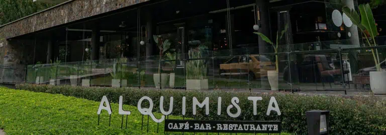 ALQUIMISTA 咖啡酒吧餐厅，位于波哥大，拥有现代化的外观、大窗户和优雅的装饰，周围环境绿意盎然。