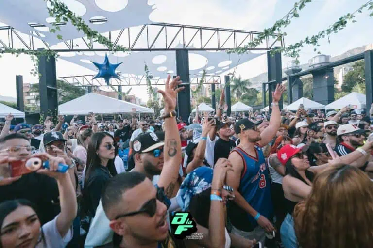 Open-air concert with a multitude of attendees enjoying live music at an event organized by Eventario in Colombia. A diverse audience, a festive atmosphere, and a stage with modern, natural decor.
