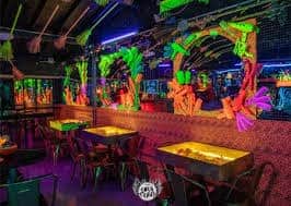 Decoración vibrante y moderna en un evento o centro de entretenimiento con iluminación neon y detalles en colores neón para una experiencia inolvidable.
