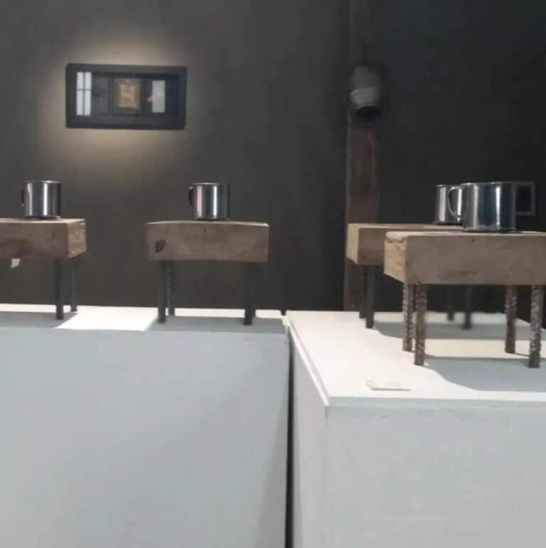 Barra de prueba de concepto con pequeños recipientes de metal sobre bases de madera en una exposición de diseño industrial.