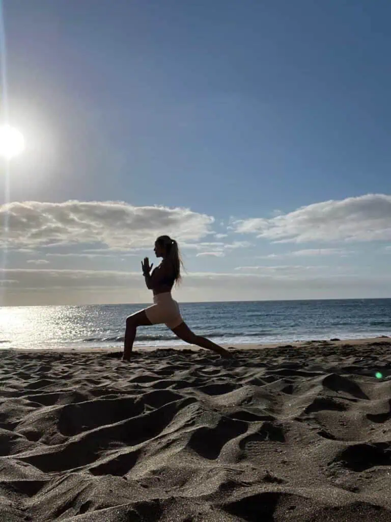 Méditation sur la plage au coucher du soleil, une femme pratiquant le yoga pour le bien-être, un événement santé et bien-être, une cérémonie de relaxation au bord de la mer, tranquillité et pleine conscience sur le sable.