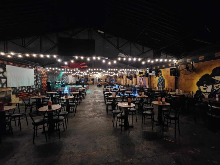 Amplia sala de eventos en interior con decoraciones modernas, mesas redondas y luces ambientales perfectas para conciertos, fiestas o reuniones empresariales en Colombia.