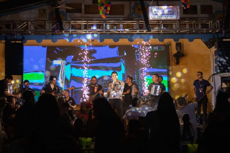 Invitación a evento con banda en vivo en un espacio cerrado con escenario y efectos de luz y confeti, presentación de música folklórica y entretenimiento en vivo para bodas, fiestas y eventos especiales en Colombia.
