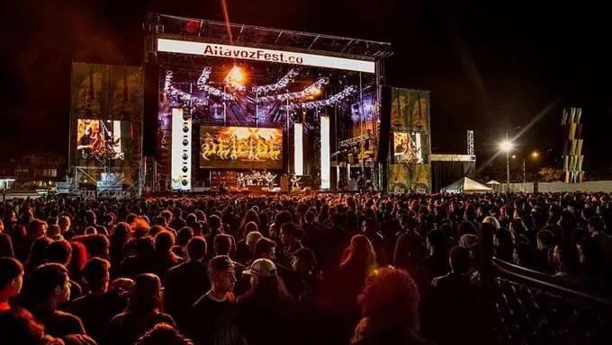 Audience at a live music festival at night, with a large crowd enjoying the outdoor event.