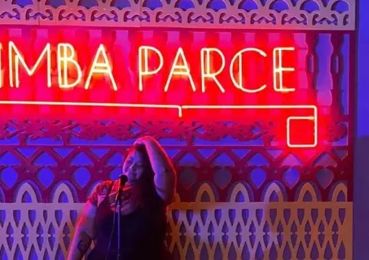 A woman on a stage with red neon signs, at an event in Bogotá, Colombia, under the theme of events and parties, promoting the organization and planning of events with Eventario.