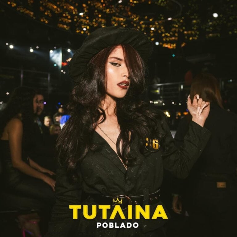 Chica en evento nocturno con estilo elegante, maquillaje y peinado sofisticado, vestida con prendas negras y accesorios glamorosos, en ambiente festivo y lleno de luces brillantes en el fondo.