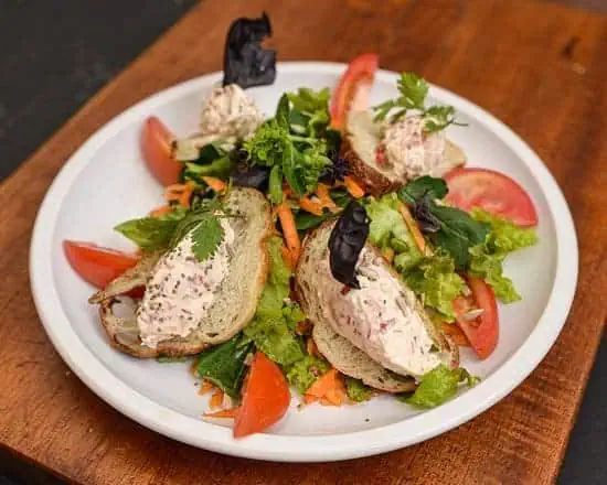 白色盘子上放着一片面包、新鲜沙拉和奶油，是波哥大举办活动和会议的健康美味之选。